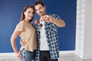 uomo e donna che sorridono abbracciati con in mano le chiavi di casa