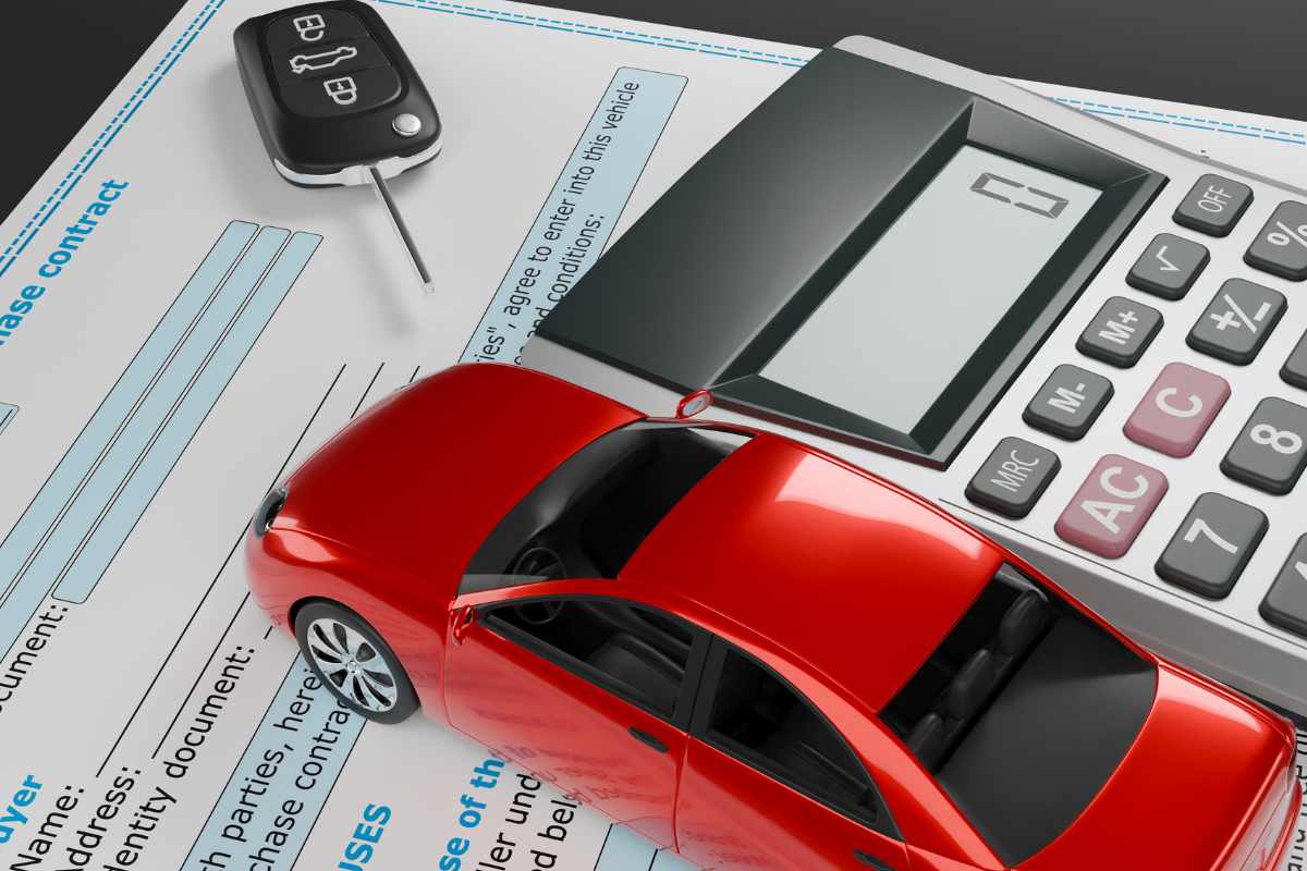 Un documento su un tavolo con sopra penna, calcolatrice, delle chiavi auto ed una chiave in miniatura