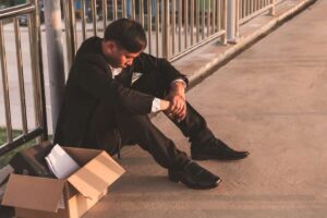 Un disoccupato che sta per strada con una scatola accanto
