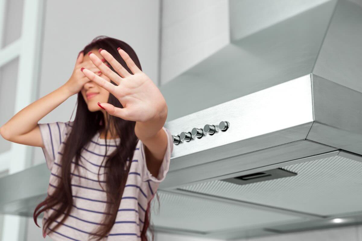 Donna con mano sugli occhi e l'altra mano fa stop, cappa da cucina classica