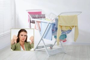 bucato steso sullo stendipanni in casa e donna che disapprova con i pollici rivolti verso il basso