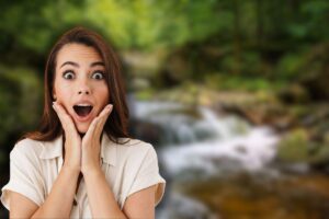 cascate sullo sfondo e donna sorpresa con mani in faccia