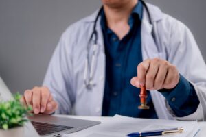 dottore che mette timbro su certificato medico