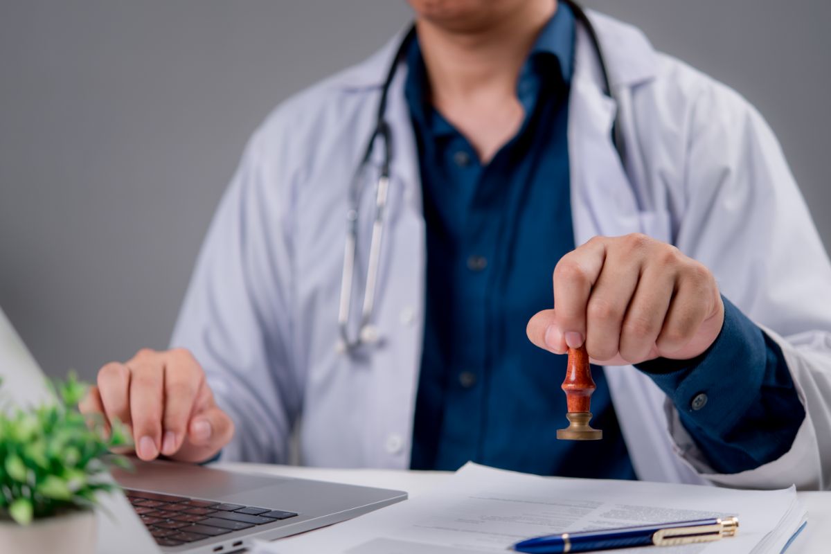 dottore che mette timbro su certificato medico