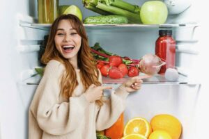 Donna indica cotone nel frigorifero pieno di cibo