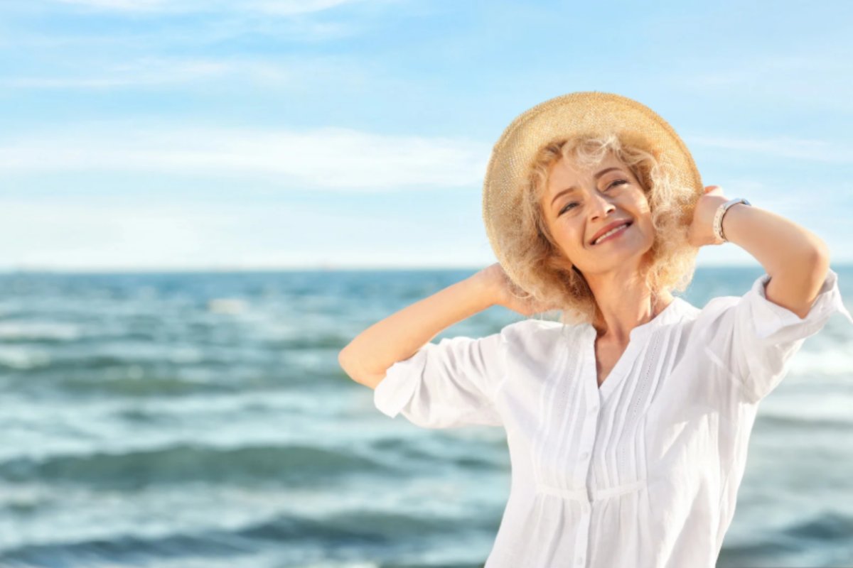 jene-stephaniuk-lkmGeyLItrw-unsplash-ls donna anziana sorridente al mare con in testa un cappello