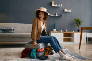 ragazza seduta sopra ad una valigia piena di vestiti