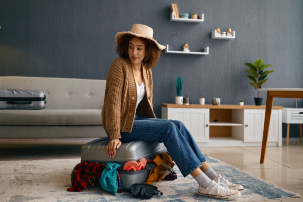 ragazza seduta sopra ad una valigia piena di vestiti