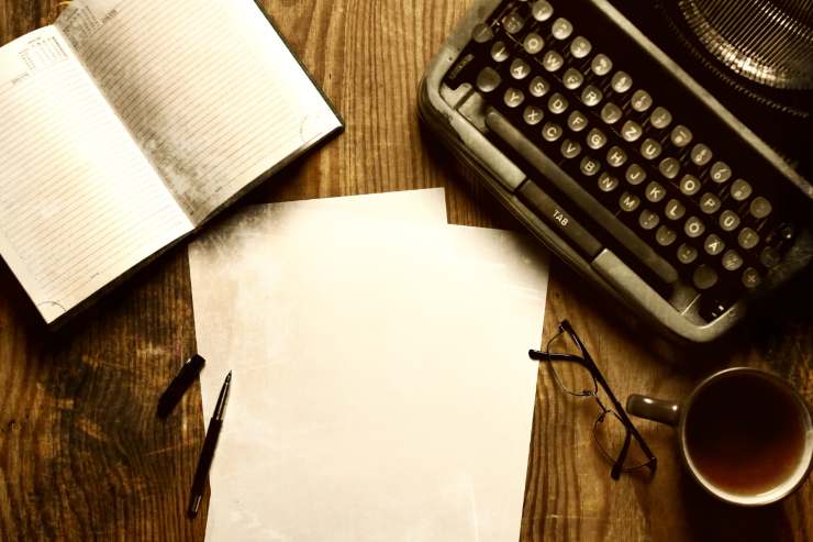 Un tavolo con dei fogli bianchi ed una macchina da scrivere