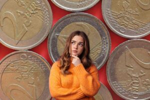 Delle monete da due euro ed una ragazza dubbiosa in primo piano