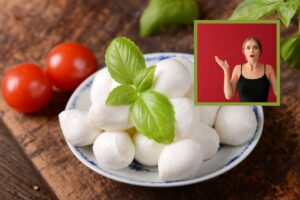 bocconcini di mozzarella in un piatto con sopra delle foglie di basilico e donna con espressione allarmata