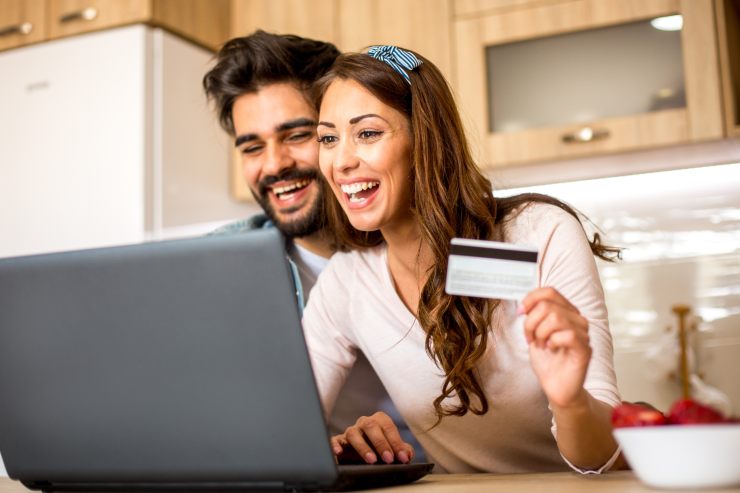 Una coppia felice con la carta di debito in mano che sta pagando online