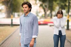 uomo che volta le spalle e se ne va mentre una donna piange