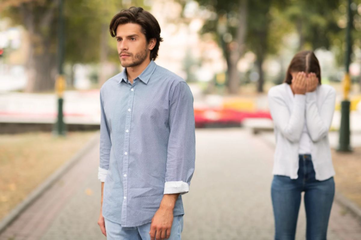 uomo che volta le spalle e se ne va mentre una donna piange