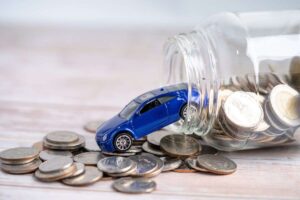 una automobilna blu che esce da un barattolo pieno di monetine