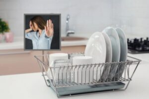 piatti dentro allo scolapiatti e nel riquadro una donna che si benda gli occhi e mette una mano davanti per dire di no