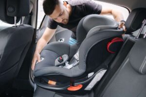 un ragazzo che mette il seggiolino in macchina