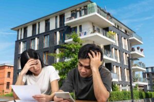 Un condominio come sfondo e due condomini in primo piano che devono pagare le spese