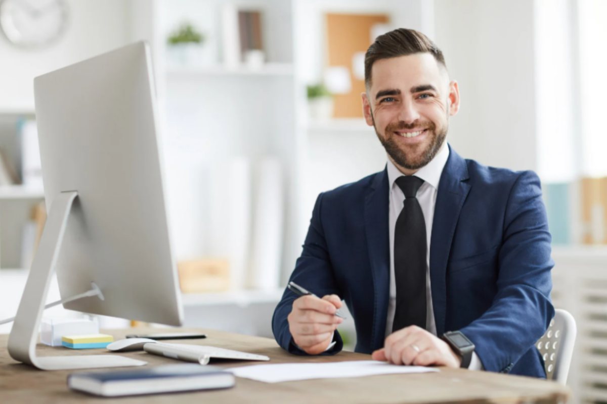 lavoratore che sorride seduto alla scrivania davanti al computer