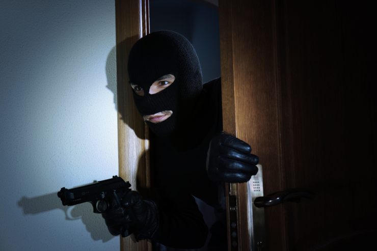 un ladro con una pistola che fa capolino da una porta 