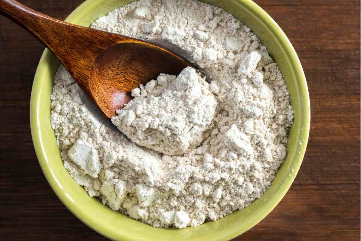 Farina in ciotola, cucchiaio di legno